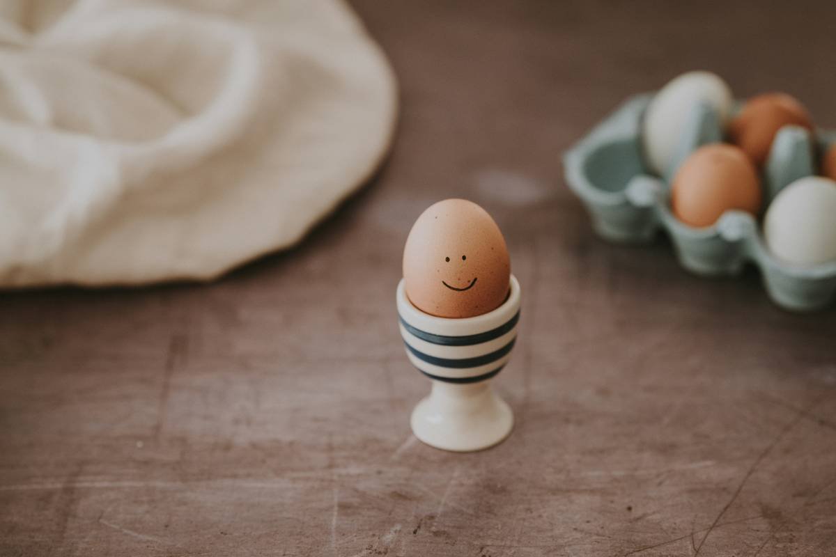 Side-by-side photo: traditional poached egg (ragged edges) vs. egg poacher result (neat, oval shape)