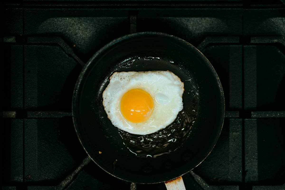 Infographic showing how egg age affects poaching: fresh eggs hold shape, older eggs spread. Includes USDA storage temp guidelines and vinegar ratio recommendations.