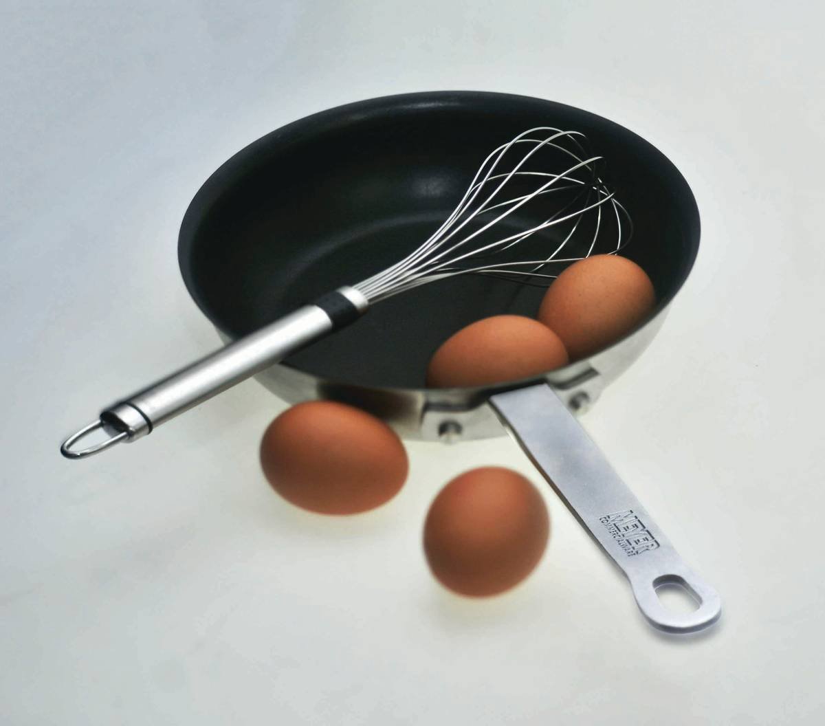 Stainless steel egg poaching rings placed in simmering water with whole eggs inside, mid-cook, showing clear definition and intact whites